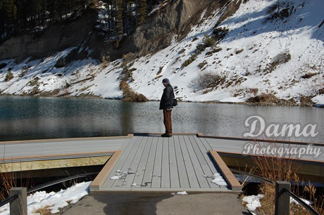 Visitor standing on the dock at Mount Lorette Ponds, Kananaskis, Alberta, Canada